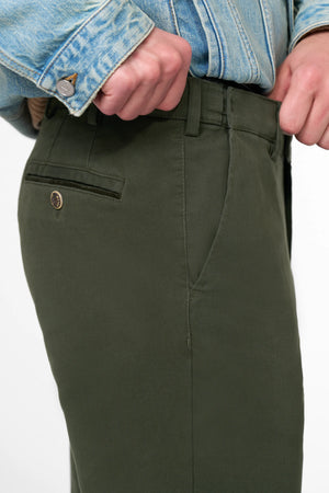 Close-up of green pants with a denim jacket on a white background