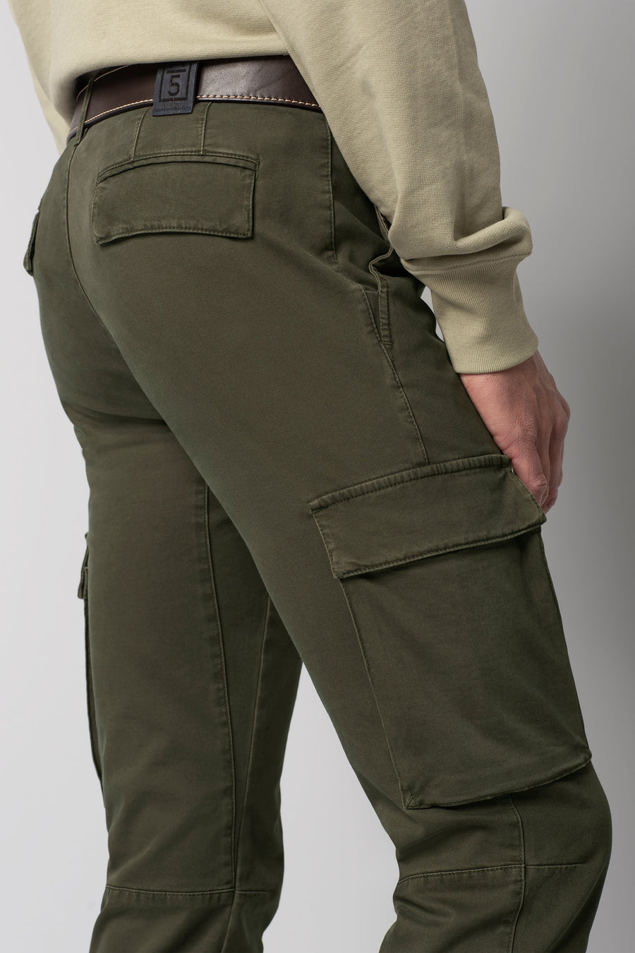 Person wearing olive green cargo pants on a plain background